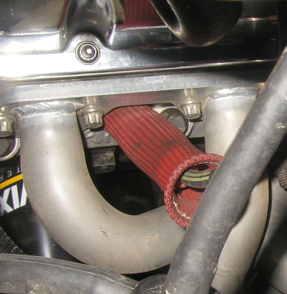Close-up of exhaust manifold with red heat shield and metal pipes