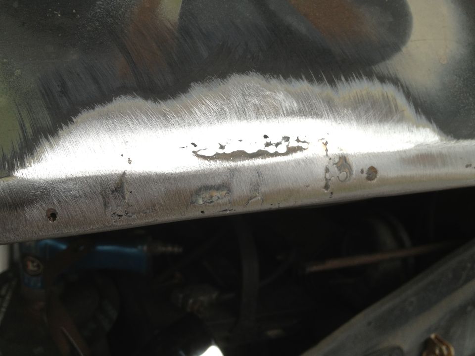 Close-up of a metal panel showing grinding marks, rust, and some pitting
