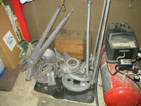 1995 Ford Bronco - Various vehicle suspension parts are piled together, alongside an air compressor and storage items.