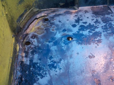 1978 Ford Bronco - The interior floor pan of a vehicle shows significant rust and damage, with multiple holes visible.