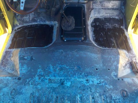 1978 Ford Bronco - The interior floor pan of a vehicle, stripped down and showing signs of rust and repair work.