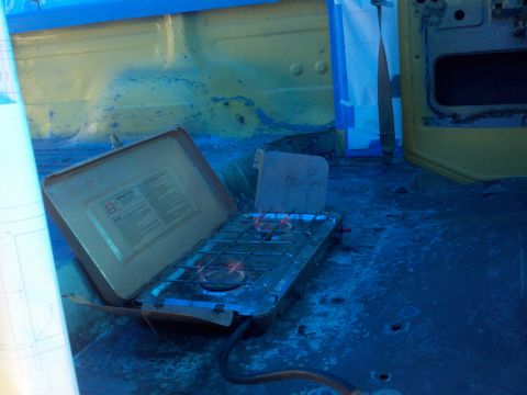 1978 Ford Bronco - A portable propane stove is set up inside a vehicle, possibly for camping or work.