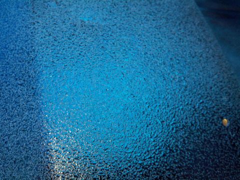 1978 Ford Bronco - A close-up shows a textured blue surface, possibly a car's paint job, with water droplets.