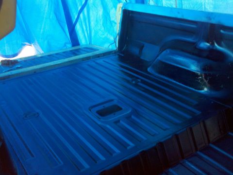 1978 Ford Bronco - The interior of a truck bed is visible, covered by a blue tarp in the background.