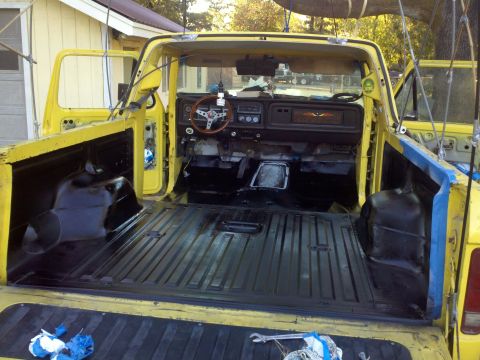 1978 Ford Bronco - Interior and bed of a yellow pickup truck, likely undergoing restoration work.