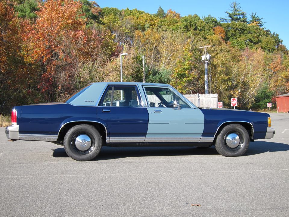 1991 Ford Crown Victoria LTD, two-tone blue and light blue paint, parked outdoors with autumn trees in background