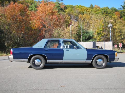 1991 Ford LTD Crown Victoria - A two-tone sedan is parked outdoors during the fall season, with colorful trees behind it.