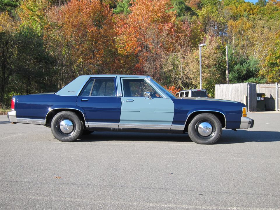 Side view of a two-tone blue 1991 Ford Crown Victoria LTD sedan with chrome hubcaps
