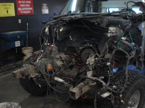 1994 Ford Bronco - Vehicle chassis undergoing disassembly, with engine and wiring exposed.