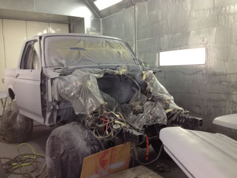 1994 Ford Bronco - A Ford truck is being prepped for paint in a booth, with its front end partially dismantled.