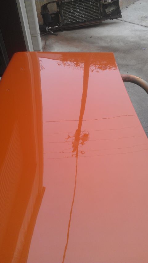 1973 Chevrolet Camaro - Reflections on a freshly painted car hood show a utility pole and wires overhead. A radiator is in the background.