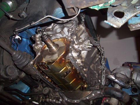 1995 Ford Probe - Engine assembly being lowered, with visible oil pan and drive axle components.