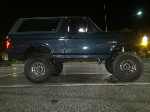 1995 Ford Bronco - This lifted Ford Bronco is shown from the side at night in a parking lot.