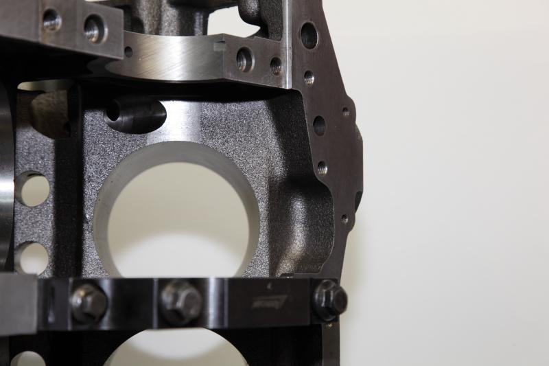Close-up of a cast iron engine block with machined bores and bolt holes