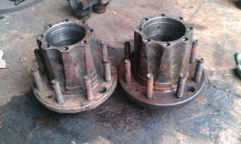 1995 Ford Bronco - Two rusty wheel hubs with multiple studs are shown resting on a workbench surface.