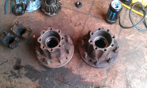 1995 Ford Bronco - Two wheel hubs and associated parts are laid out on a workbench.