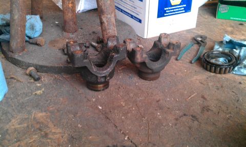 1995 Ford Bronco - Differential pinion yokes and a bearing are shown on a workbench, possibly for a 1995 Ford Bronco.