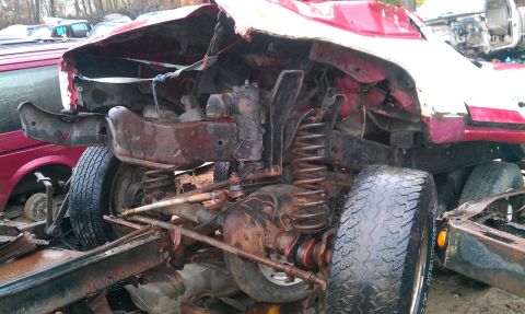 1995 Ford Bronco - This heavily damaged truck chassis shows significant damage to its front end and suspension system.
