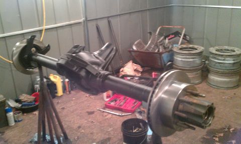 1995 Ford Bronco - A disassembled rear axle assembly is shown in a workshop setting, with tools and spare parts visible in the background.