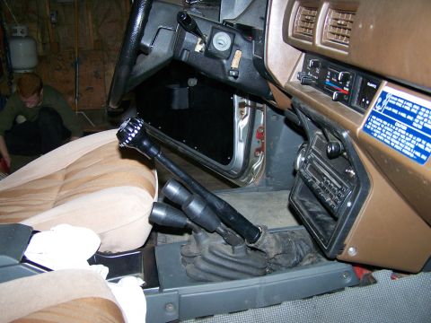 1988 Suzuki Samurai - The interior of a vehicle shows dual transfer case levers and a brown dashboard with an aftermarket radio.