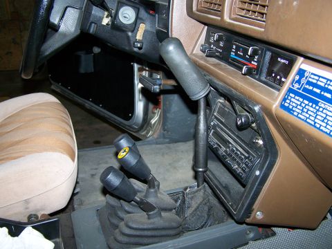 1988 Suzuki Samurai - The interior of a vehicle shows a complex gear shifter setup and an aftermarket radio.