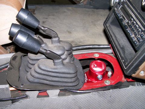 1988 Suzuki Samurai - Close-up of transfer case shifters and a red fluid reservoir in a vehicle interior.