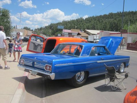 1991 Ford LTD Crown Victoria - A blue 1964 Ford Fairlane 500 is parked at an outdoor car show with its hood open.