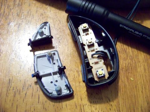 1999 Mercury Grand Marquis - The interior components of a car's mirror control panel are laid out on a wooden surface next to a flashlight.