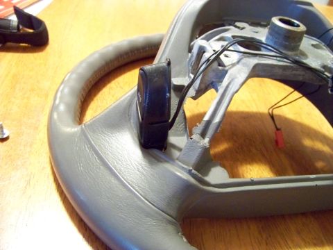 1999 Mercury Grand Marquis - Close-up of a disassembled steering wheel component, showing internal wiring and a control module.