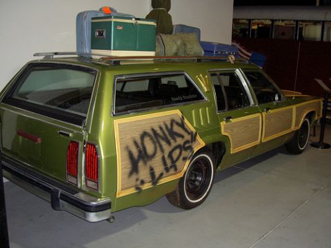 1997 Ford Ranger - A green station wagon is loaded with luggage on its roof rack and has custom wood paneling with graffiti on the doors.