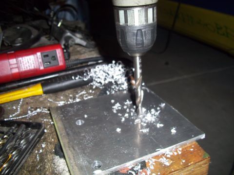 1995 Ford Probe - A drill is used to create holes in a metal plate, with metal shavings scattered around the work area.