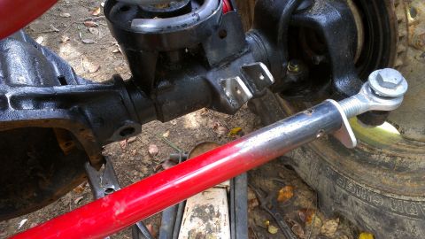 1978 Ford Bronco - Close-up of a vehicle's suspension system, showing a red and silver rod attached to a black component and tire.