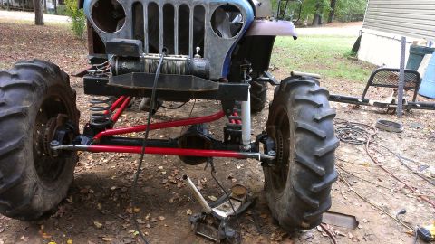 1978 Ford Bronco - This heavily modified vehicle appears to be undergoing repairs or customization with its large tires and exposed mechanical parts.