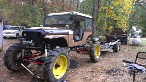 1978 Ford Bronco - This heavily modified Jeep CJ sits outdoors with a trailer attached, next to other vehicles.