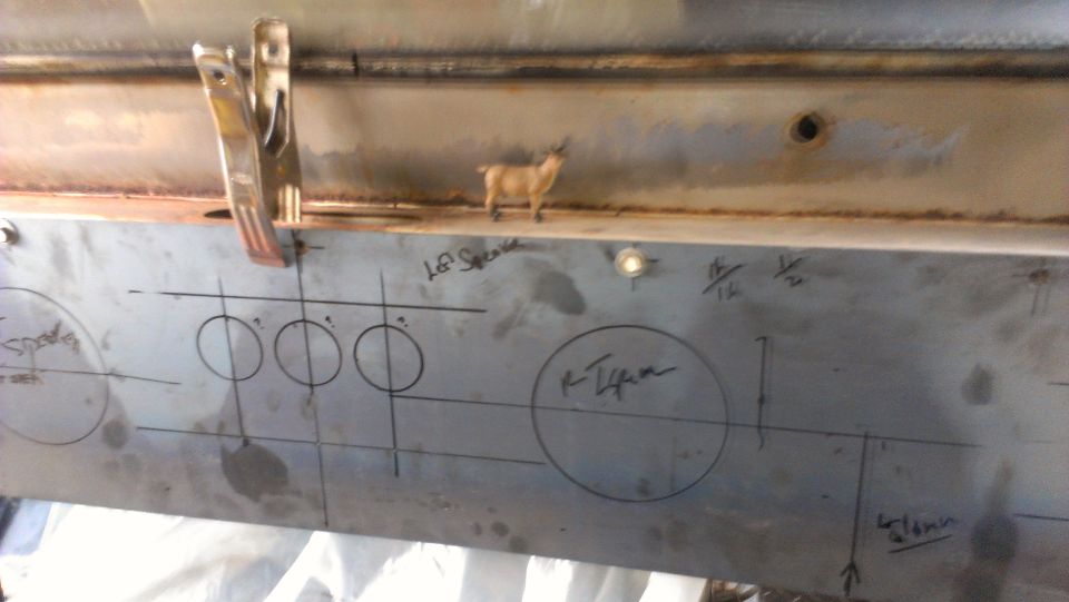 Metal panel with circles and lines drawn on it, possibly for speaker placement. A small goat figurine is on top