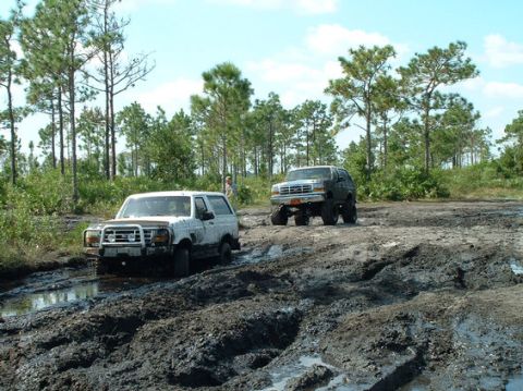 1992 Ford Bronco - Two Ford Broncos navigate a muddy off-road course during an event in October 2003.