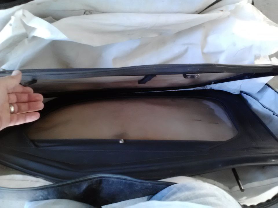 Hand reaching into a car cover, revealing a windowed section