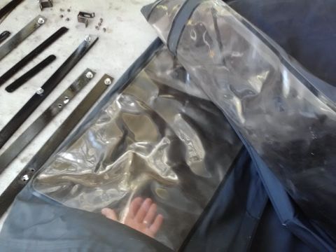 1978 Ford Bronco - Parts for a car's convertible top are laid out on a surface, including metal frame pieces and a clear plastic window.
