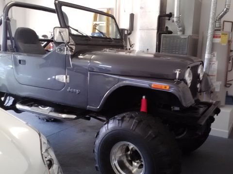 1978 Ford Bronco - A gray Jeep CJ-7 is parked in a garage, showing its side and front quarter view.