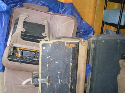 Removed tan bench seat with exposed metal frame in a cluttered garage