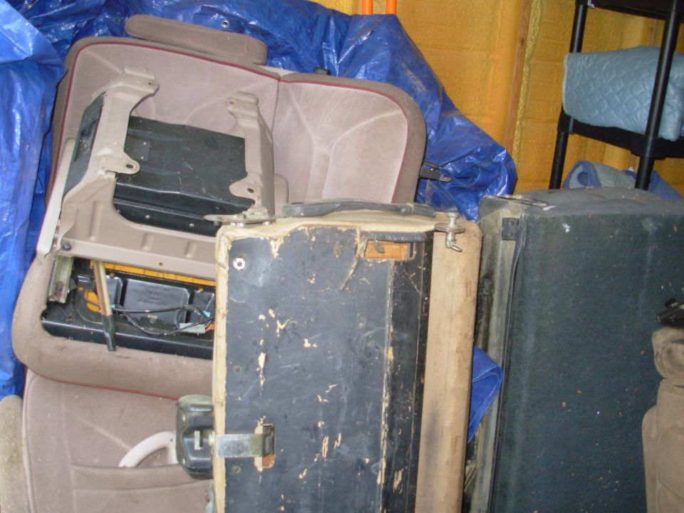 Removed tan bench seat with exposed metal frame in a cluttered garage