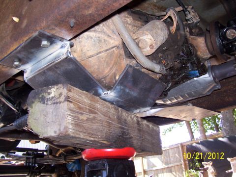 1990 Ford Bronco - Custom metal brackets and a wooden block support the transfer case of a vehicle.