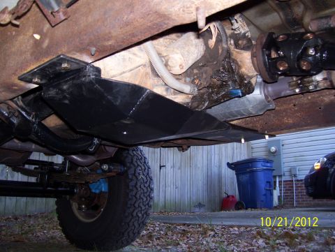 1990 Ford Bronco - Close-up view of the undercarriage of a vehicle, showing mechanical components and a skid plate.