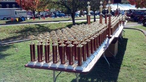 2007 Ford Mustang - Numerous trophies are lined up on tables outdoors, with cars and tents visible in the background.