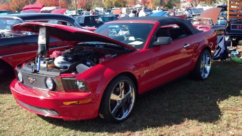 2007 Ford Mustang - A red 2007 Ford Mustang GT convertible is displayed with its hood open at a car show.