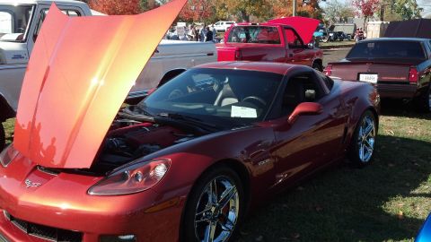 2007 Ford Mustang - A red Chevrolet Corvette is parked on grass with its hood up, alongside other vehicles.