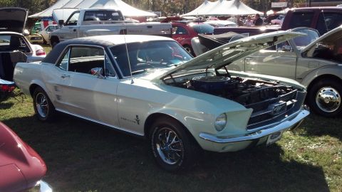 2007 Ford Mustang - Outdoor car show features a 1967 Ford Mustang coupe with its hood open.