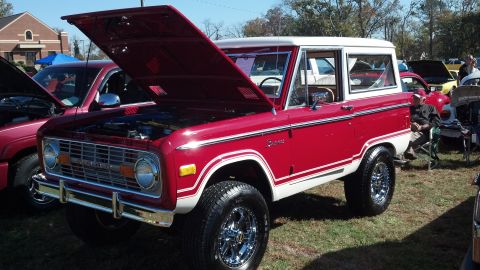 2007 Ford Mustang - A classic red and white Ford Bronco is displayed with its hood up at an outdoor event.