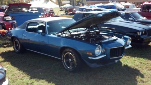 2007 Ford Mustang - A blue 1970s coupe with its hood open is parked on grass at an outdoor car show.