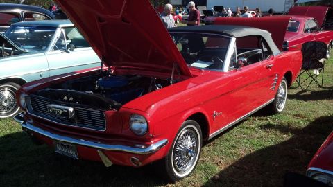2007 Ford Mustang - A classic red convertible is displayed with its hood open at an outdoor car show.